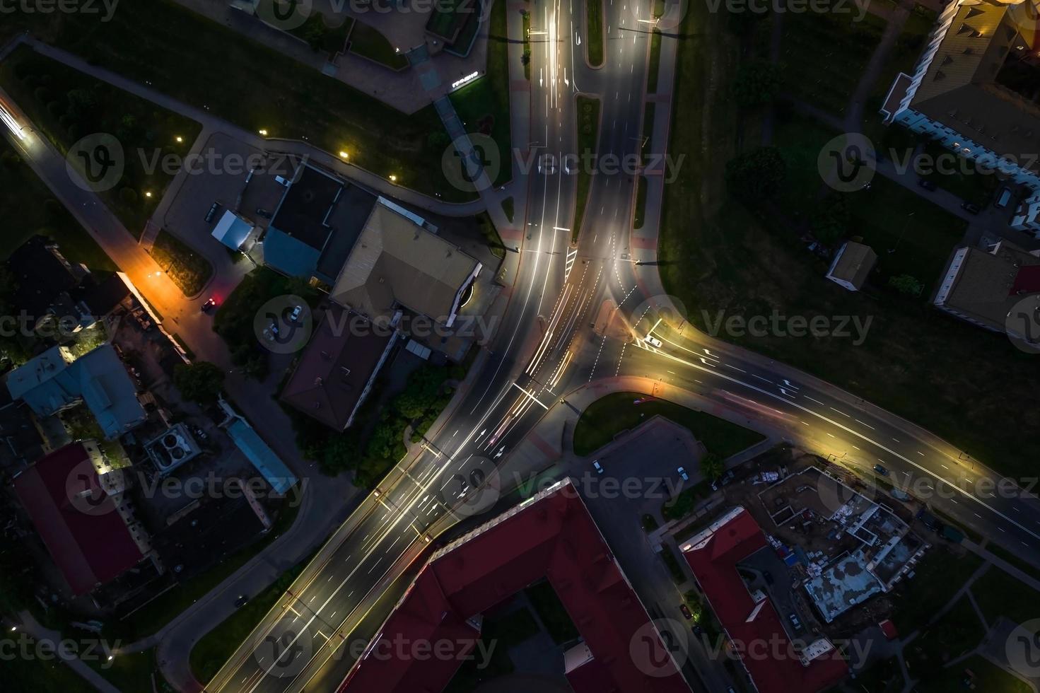 noche sobre cruce de carreteras, carretera de intersección con coches con faros en la carretera. vida nocturna en la gran ciudad. mirando hacia abajo en el tráfico foto