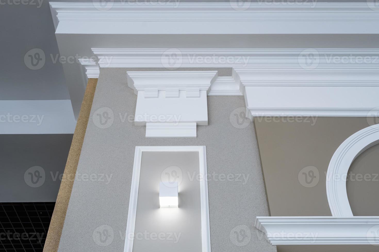 Detail of corner ceiling with intricate crown molding on column with spot light photo