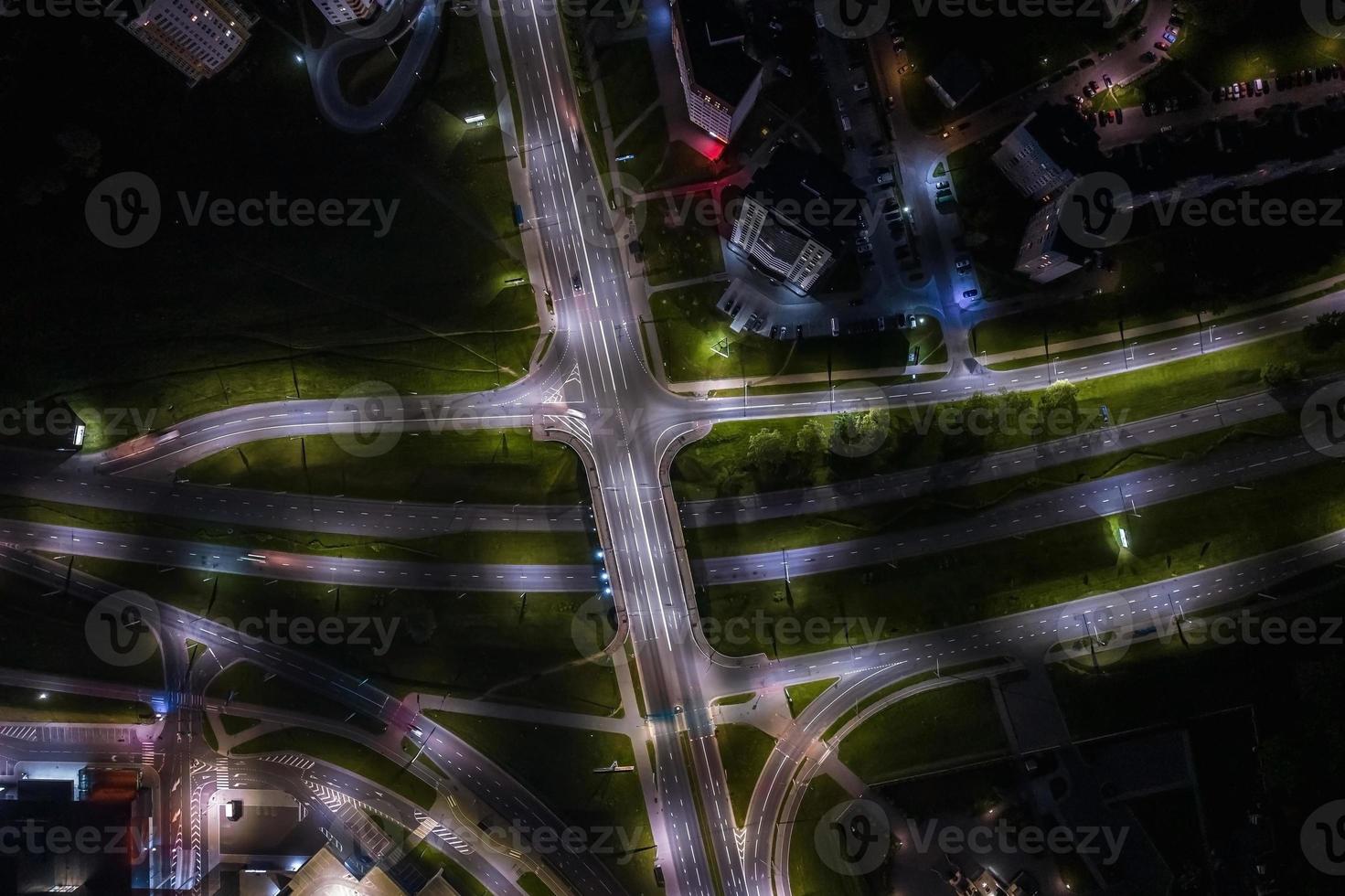 noche sobre cruce de carreteras, carretera de intersección con coches con faros en la carretera. vida nocturna en la gran ciudad. mirando hacia abajo en el tráfico foto