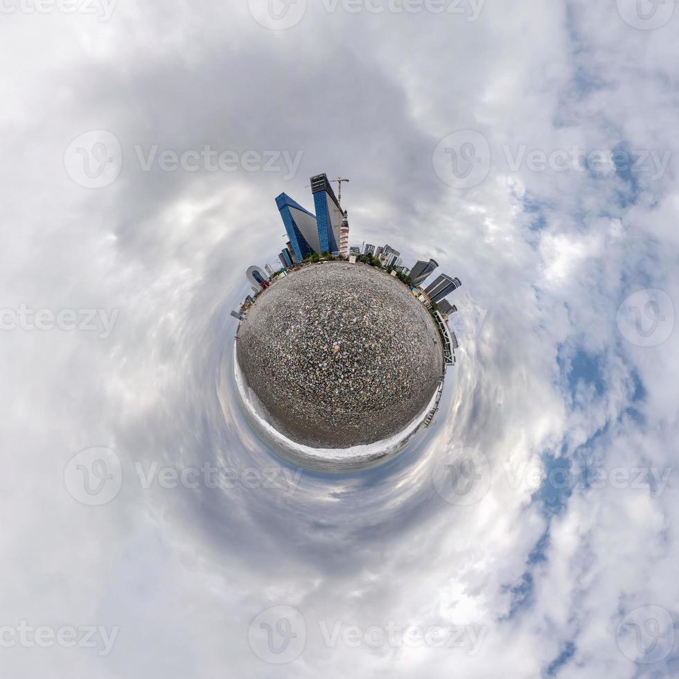 tiny planet in blue sky with clouds in city beach near modern skyscrapers or office buildings. Transformation of spherical 360 panorama in abstract aerial view. photo