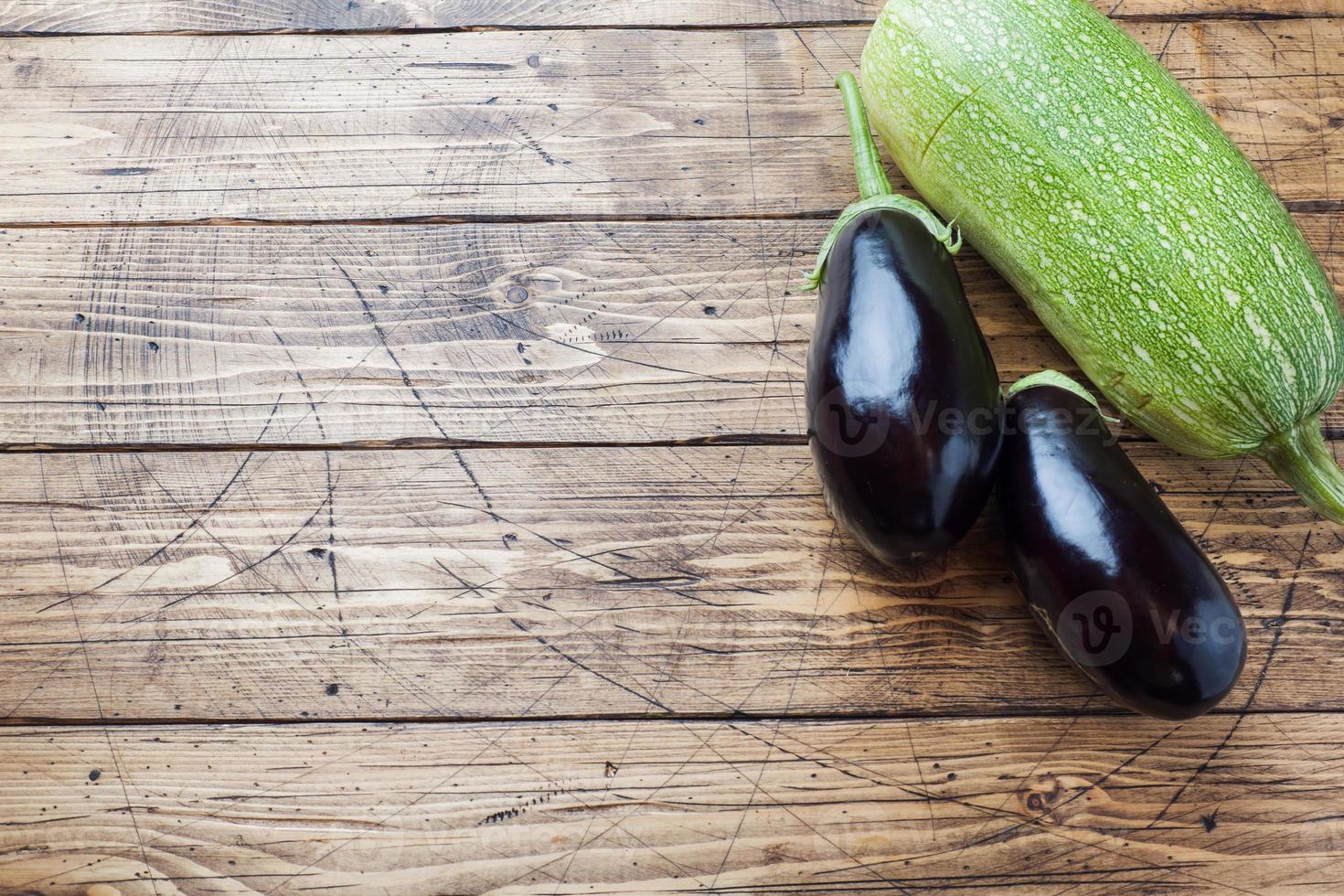 Fresh eggplant and zucchini on wooden background with copy space. photo