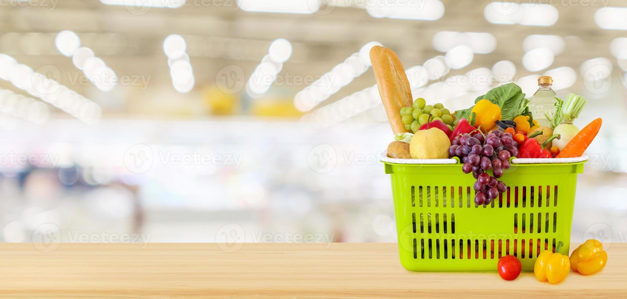 cesta de la compra llena de frutas y verduras en la mesa de madera con fondo desenfocado borroso de la tienda de comestibles del supermercado foto