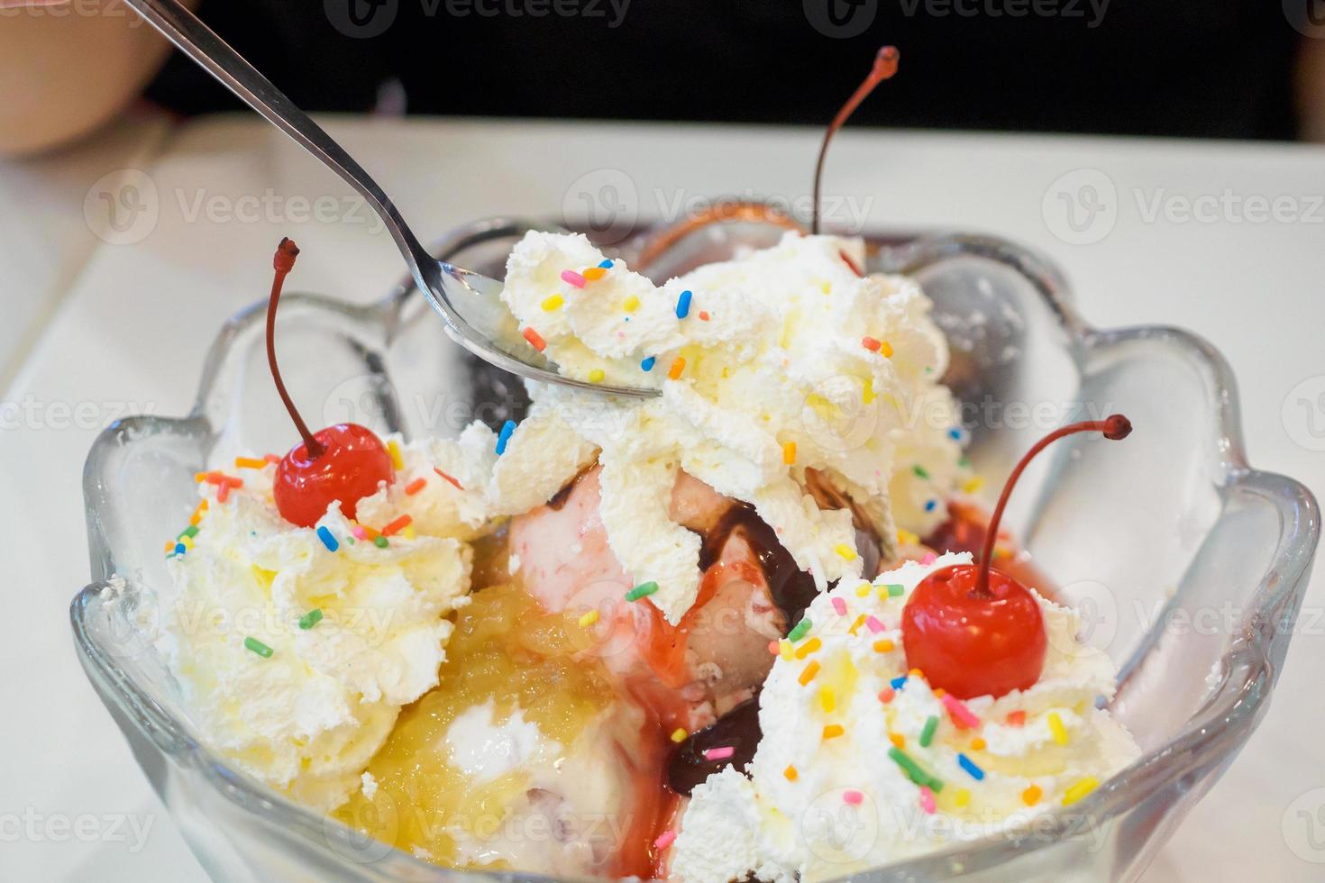 ice cream in glass bowl with whipped cream and red cherry on top photo