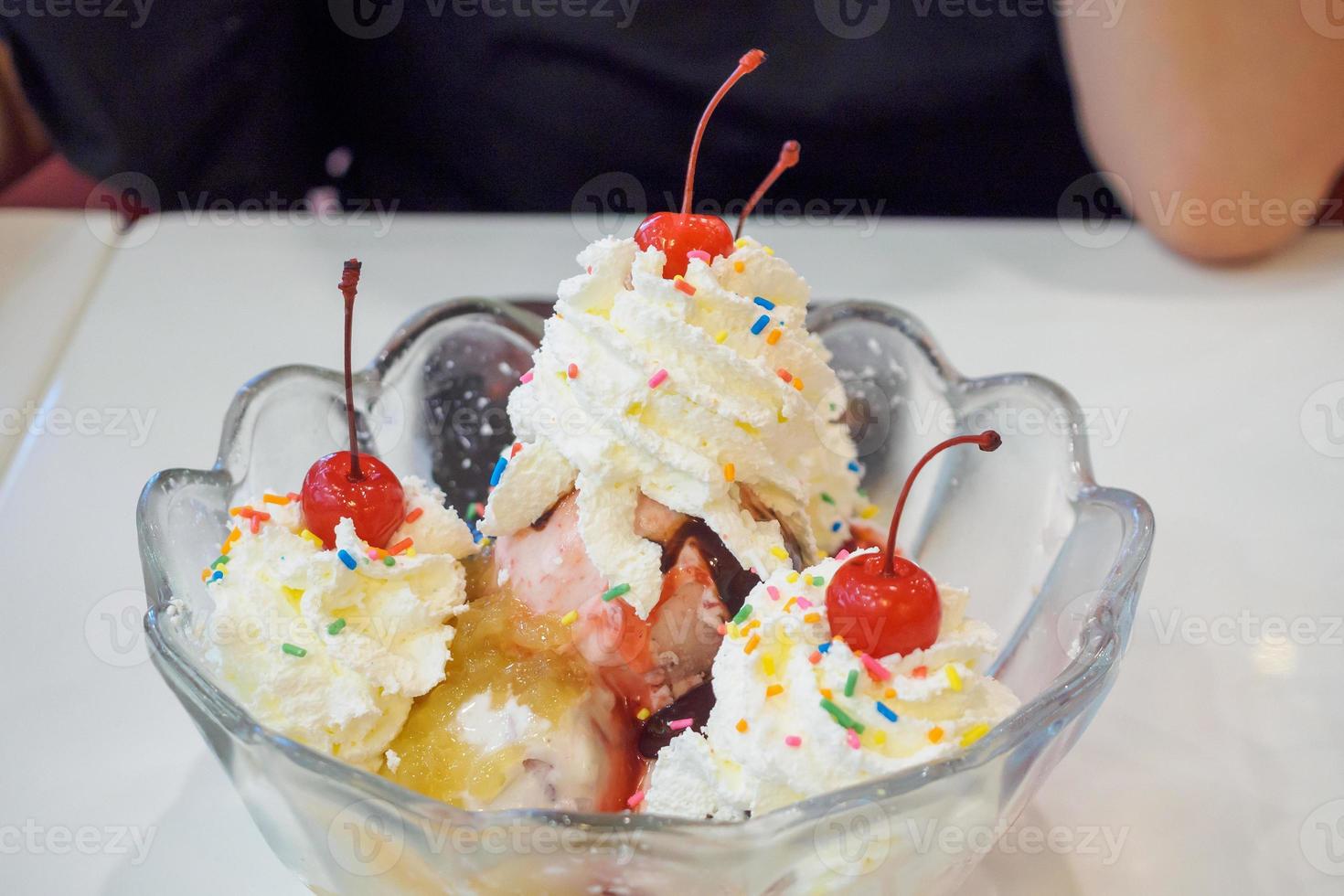 ice cream in glass bowl with whipped cream and red cherry on top photo