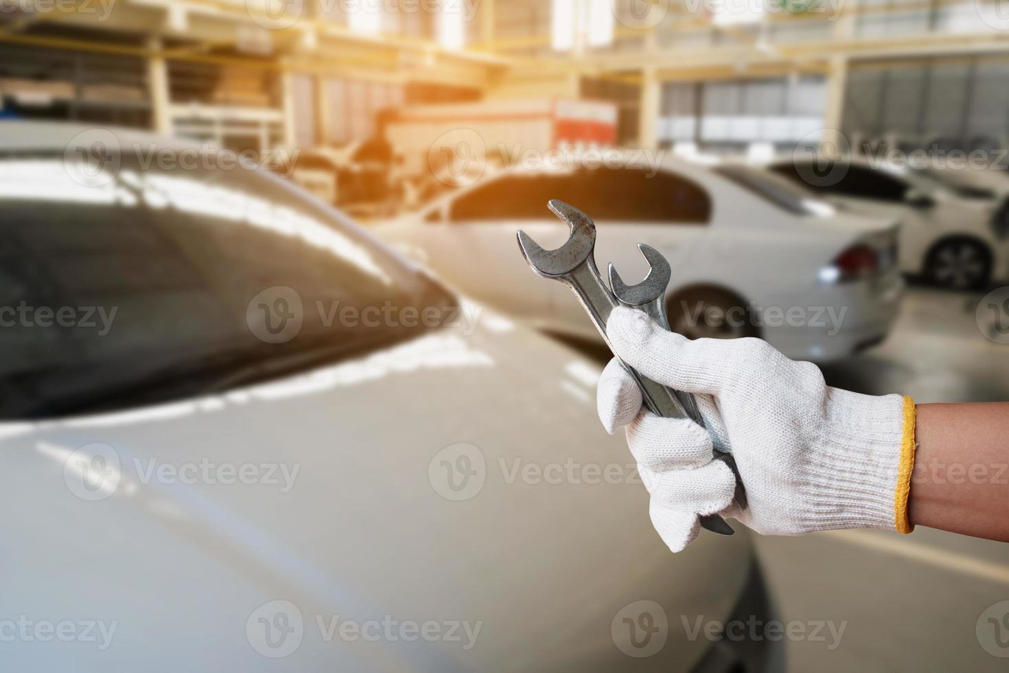 mechanic holding wrench over car repair service centre photo