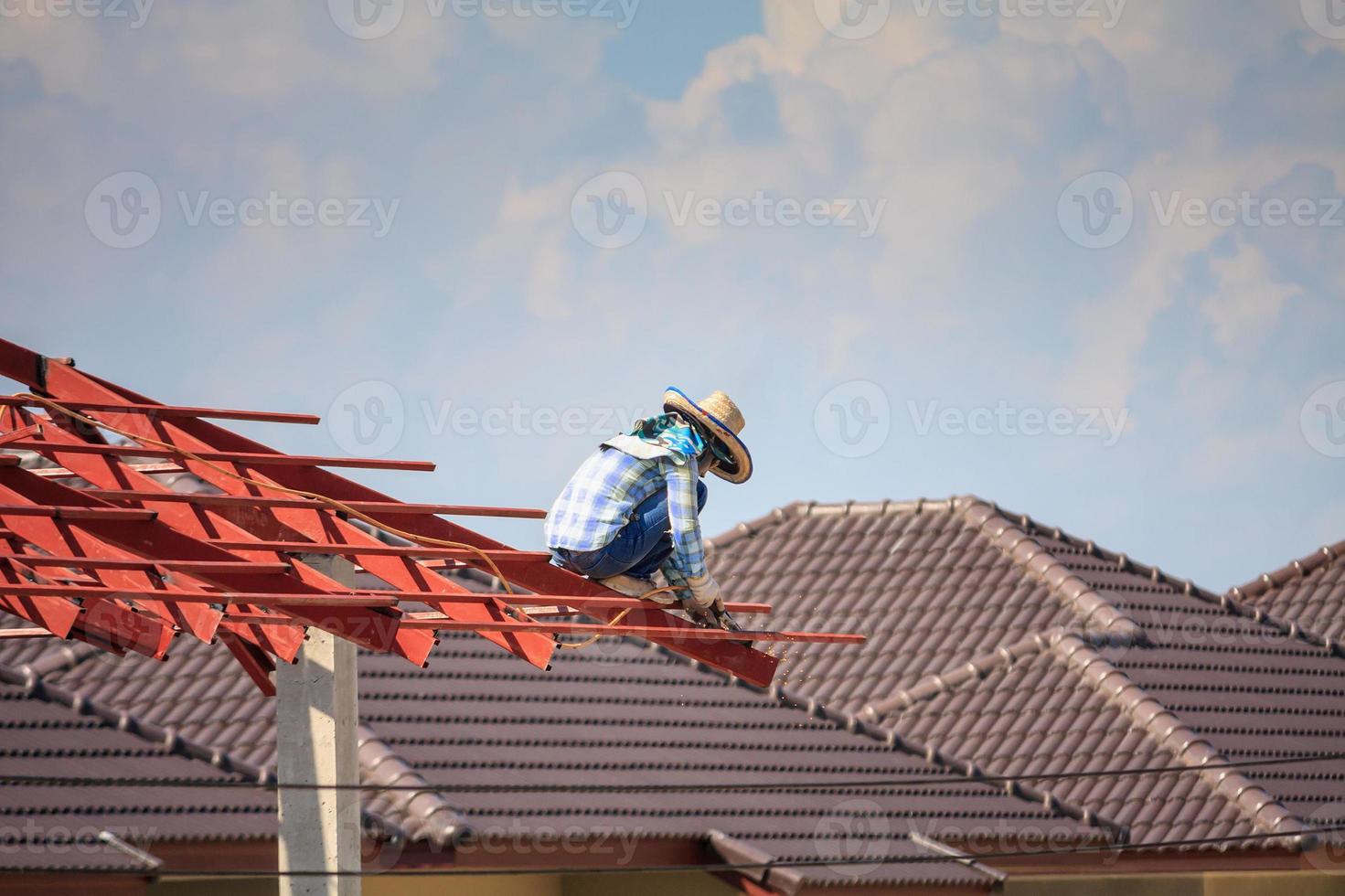 welder workers installing steel frame structure of the house roof at building construction site photo