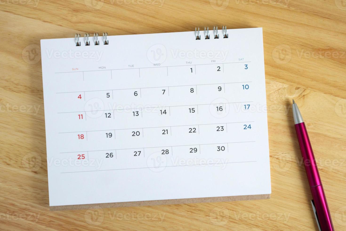 Calendar page with pen on wooden desk table photo