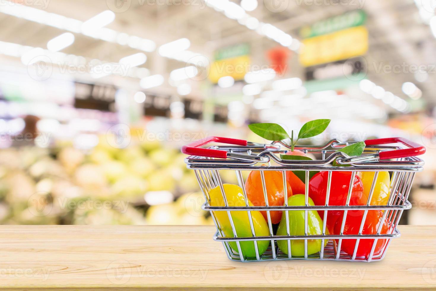 cesta de la compra con frutas en la mesa de madera sobre el fondo borroso del supermercado de la tienda de comestibles foto