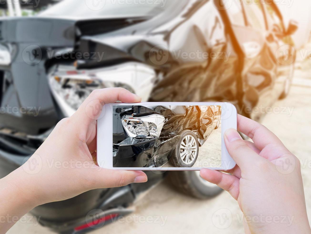 Hembra sostenga teléfono inteligente móvil fotografiando accidente automovilístico foto