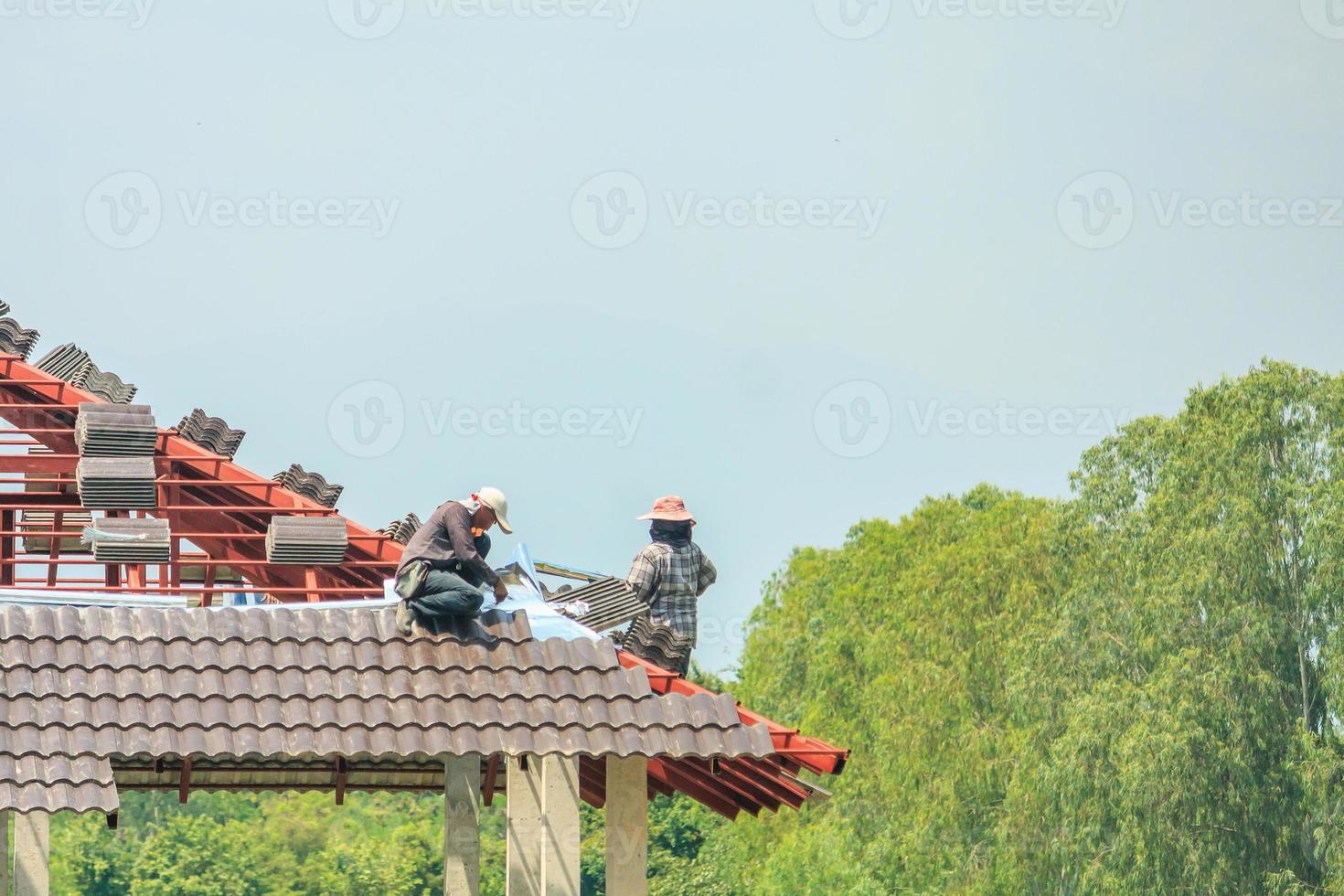 techador de construcción instalando tejas en el sitio de construcción de viviendas foto