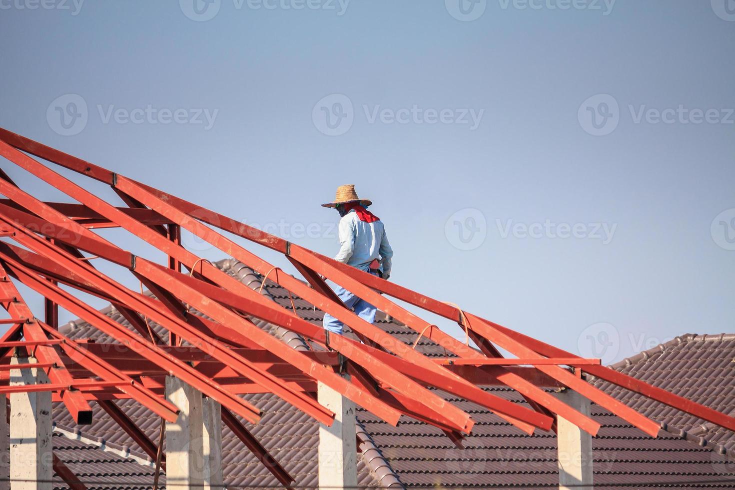 welder workers installing steel frame structure of the house roof at building construction site photo