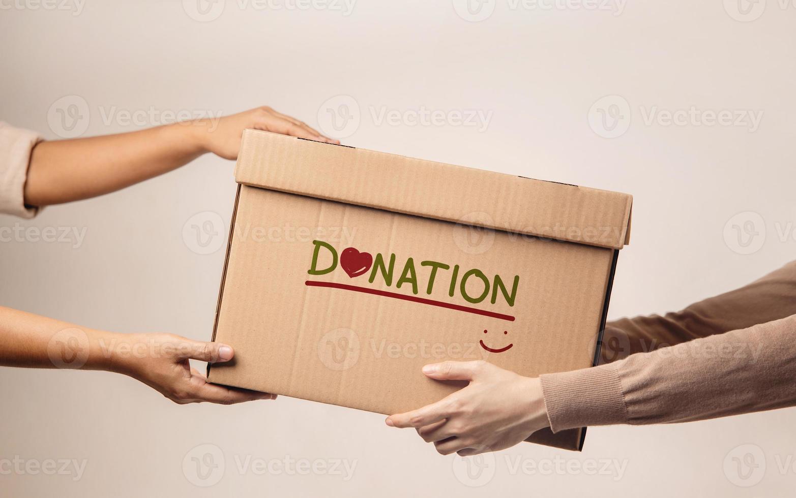 concepto de donación. el voluntario entregando una caja de donación al destinatario. de pie contra la pared foto