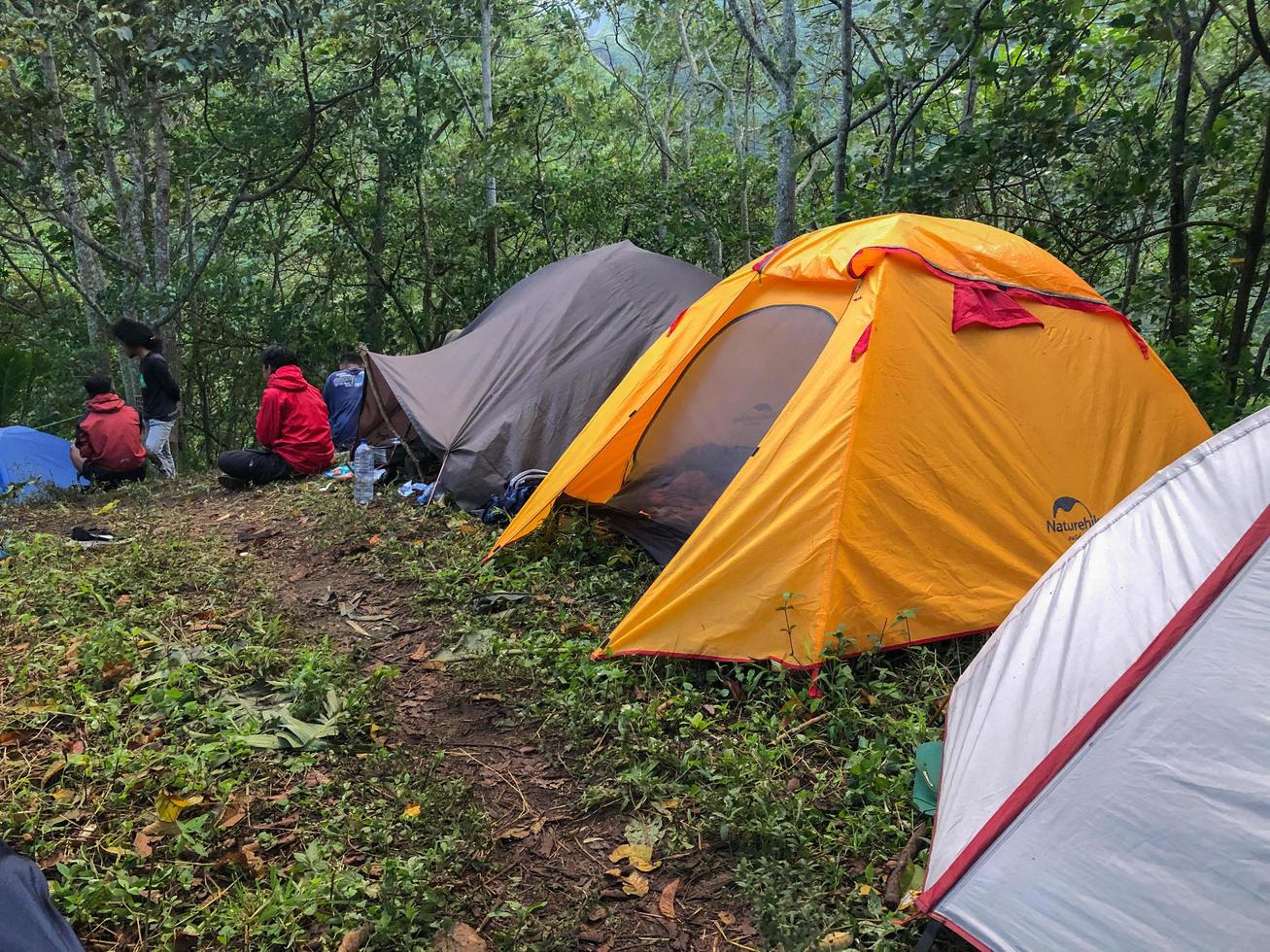 Blitar, Indonesia - August 17th 2022. Camping tents and some people chatting and enjoying in the top of mountain in the morning photo