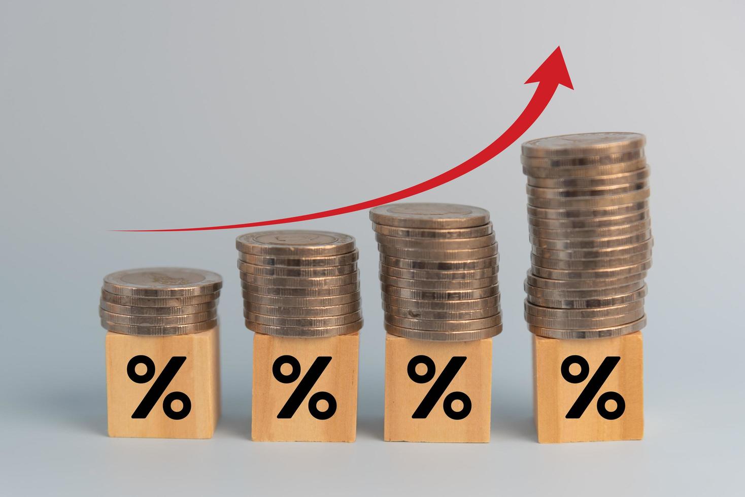 finanzas empresariales inversiones economía pila inflación de monedas y flecha roja con porcentaje de cubo de madera en el escritorio. foto