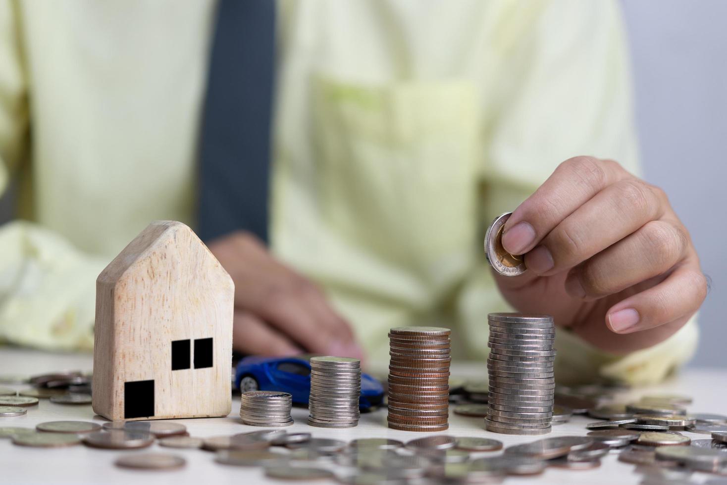 negocio de concepto de bienes raíces, seguro de hogar y protección de bienes raíces. compra y venta de casas y bienes raíces en línea. hombre que sostiene la pila de monedas en el escritorio. foto