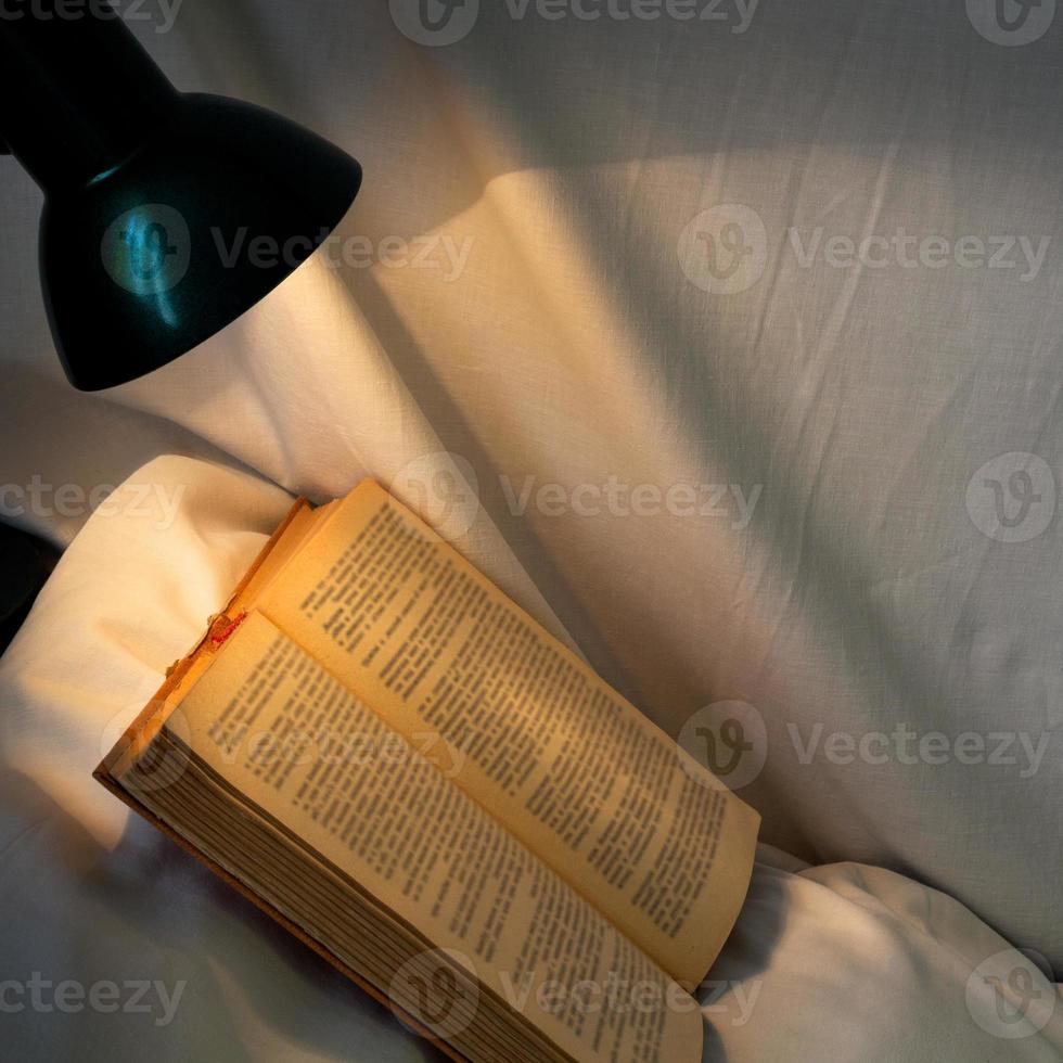 book on white pillow lit table lamp photo