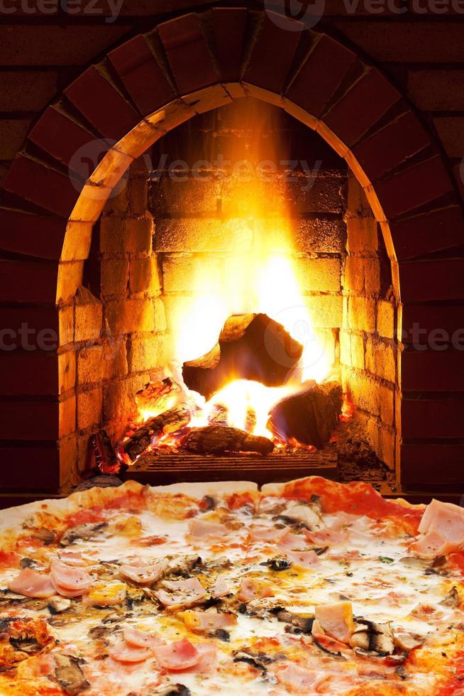 pizza with ham, mushroom and open fire in stove photo