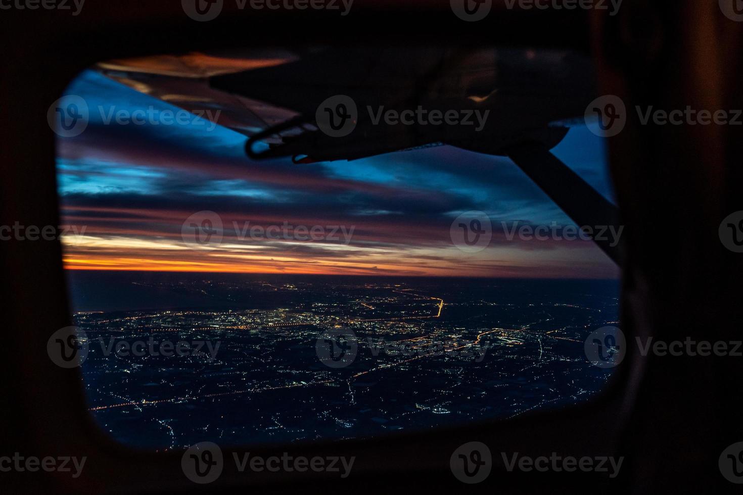 el crepúsculo de la noche desde el avión a reacción ve el cielo azul naranja rojo con la luz de la ciudad de Tailandia debajo foto