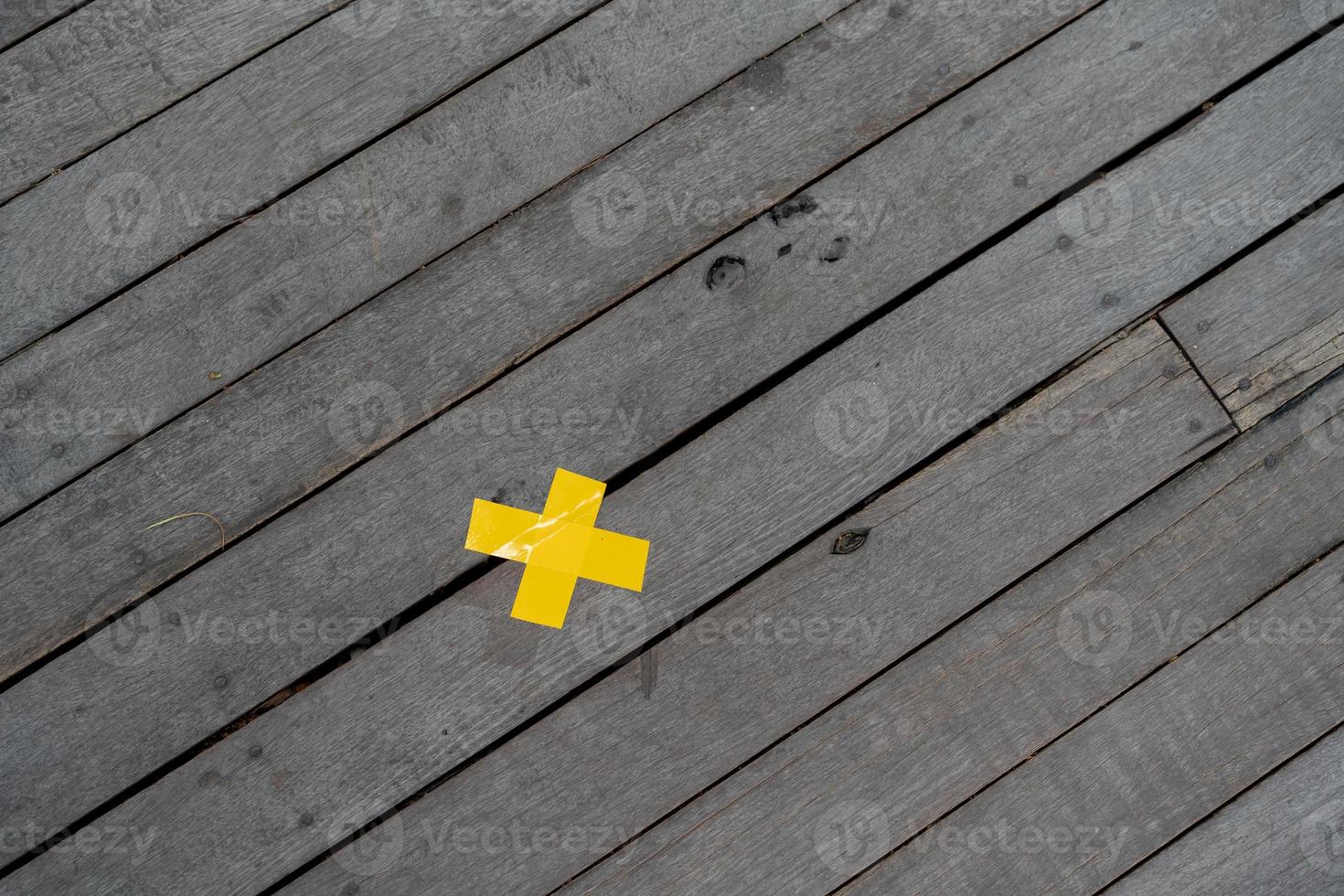 yellow cross marking tape on the wood board floor from top view shooting at outdoor field for background or backdrop photo