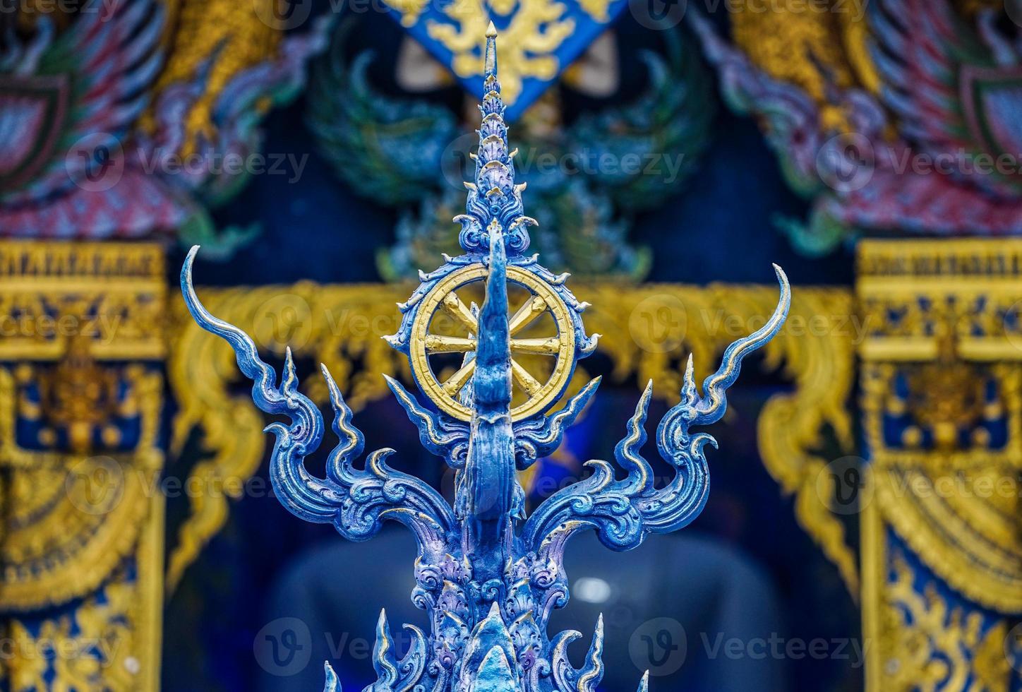 Gold rowel, the symbol of buddhist religion on the Thai blue art style pole with temple background. photo