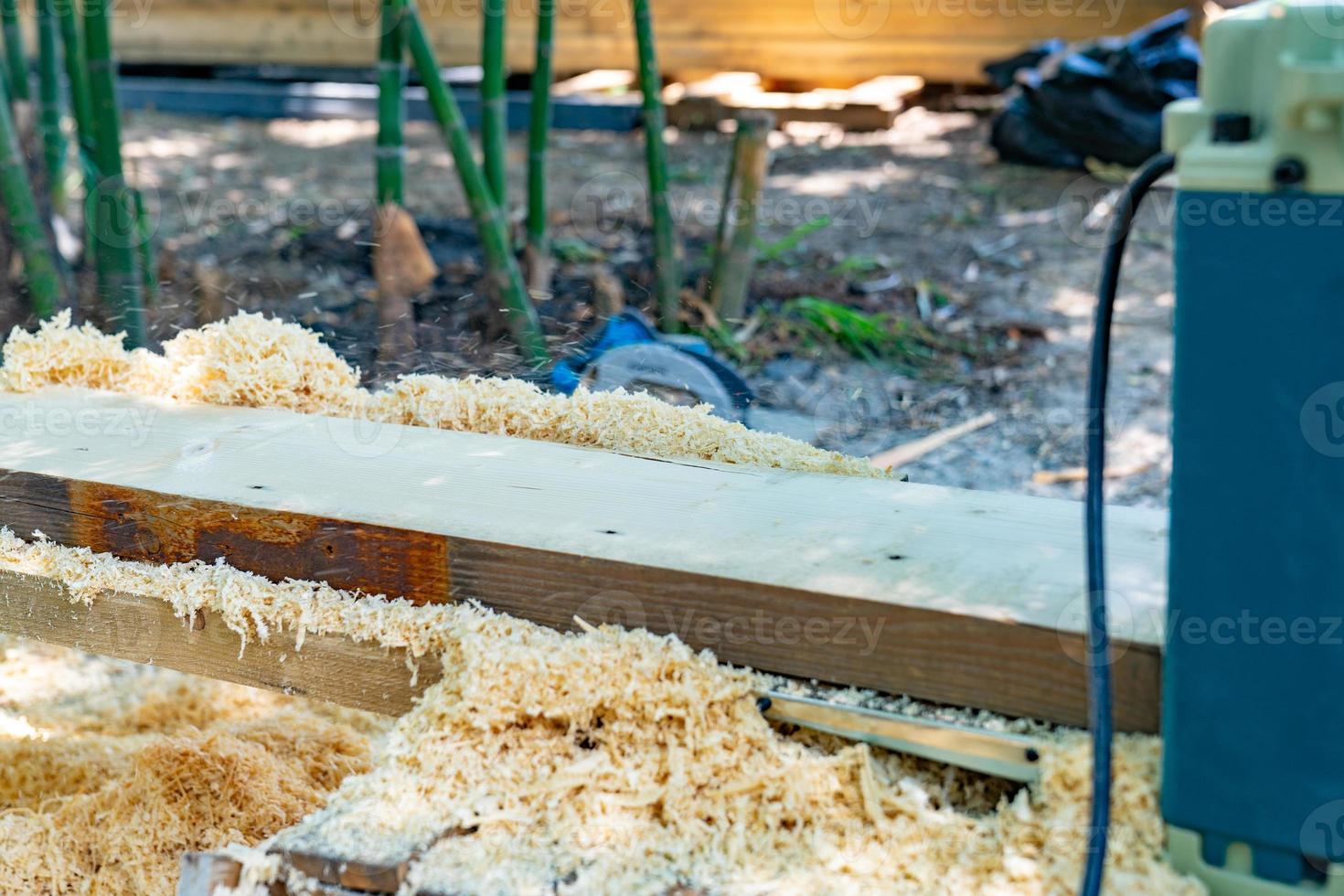 worker scrubs the big long wood plate with polishing machine in the garden. photo