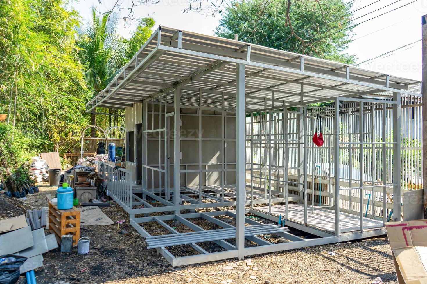 underconstruction housemaid small temporary home is made from steel pole structure without cement and brick with garden and fence around. photo