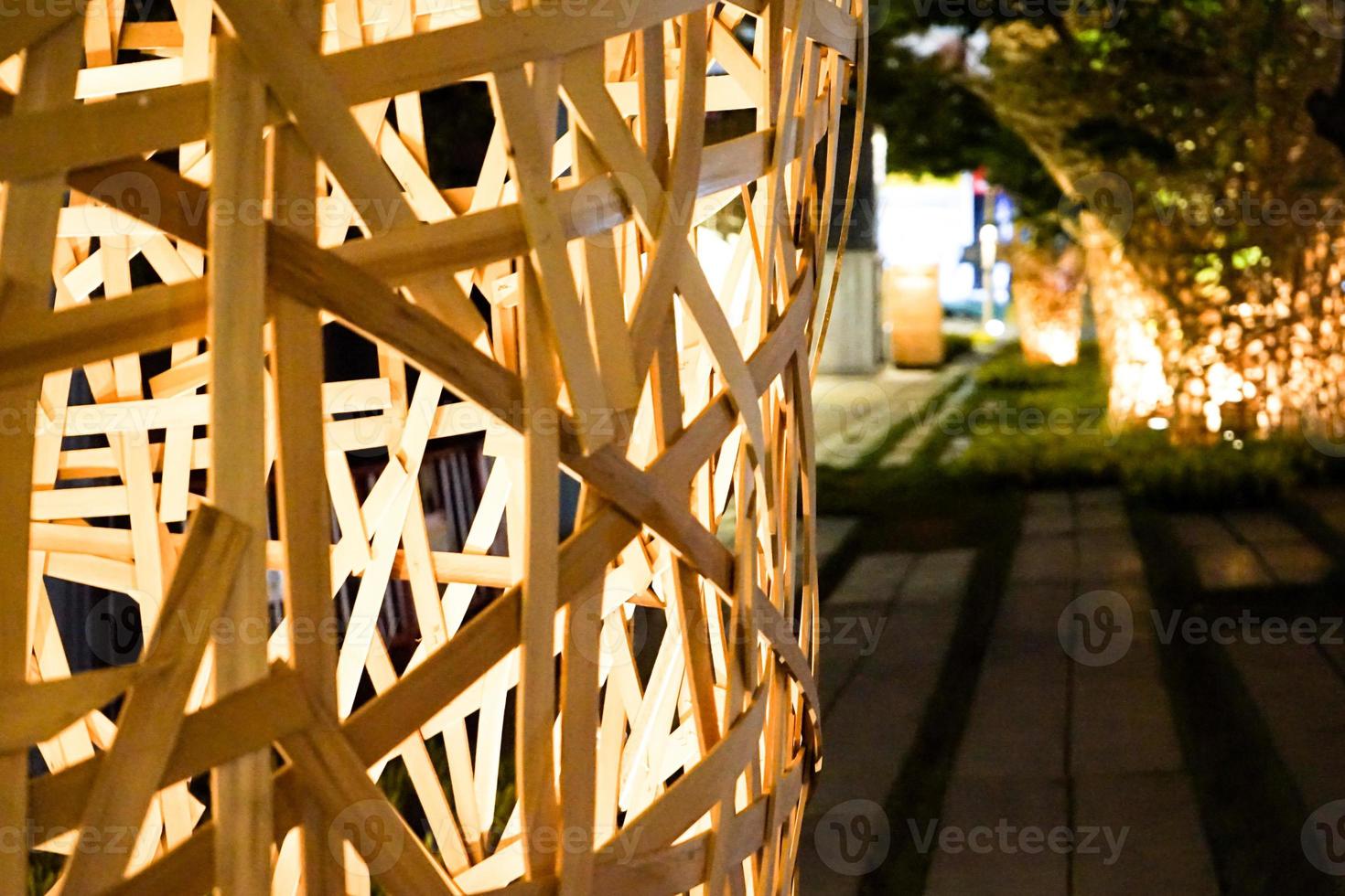 el arte decorado con grandes palos de madera se pega alrededor del árbol en la noche con luz de tungsteno colgando alrededor. foto