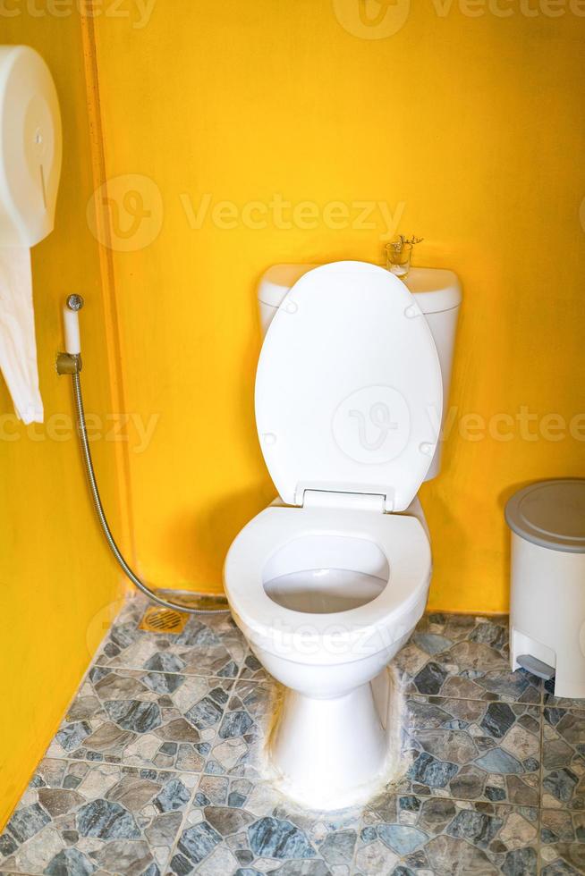 Yellow Toilet room with flush toilet, tash and toilet paper inside it. This is located in the garden. photo