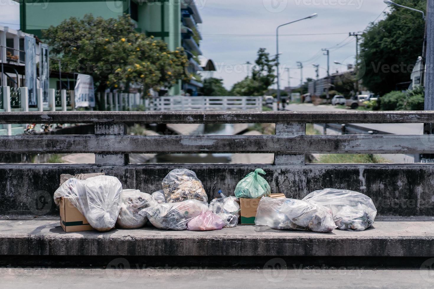 a pile of garbage are dropped on the footpath over the canal bridge in the midday time. photo
