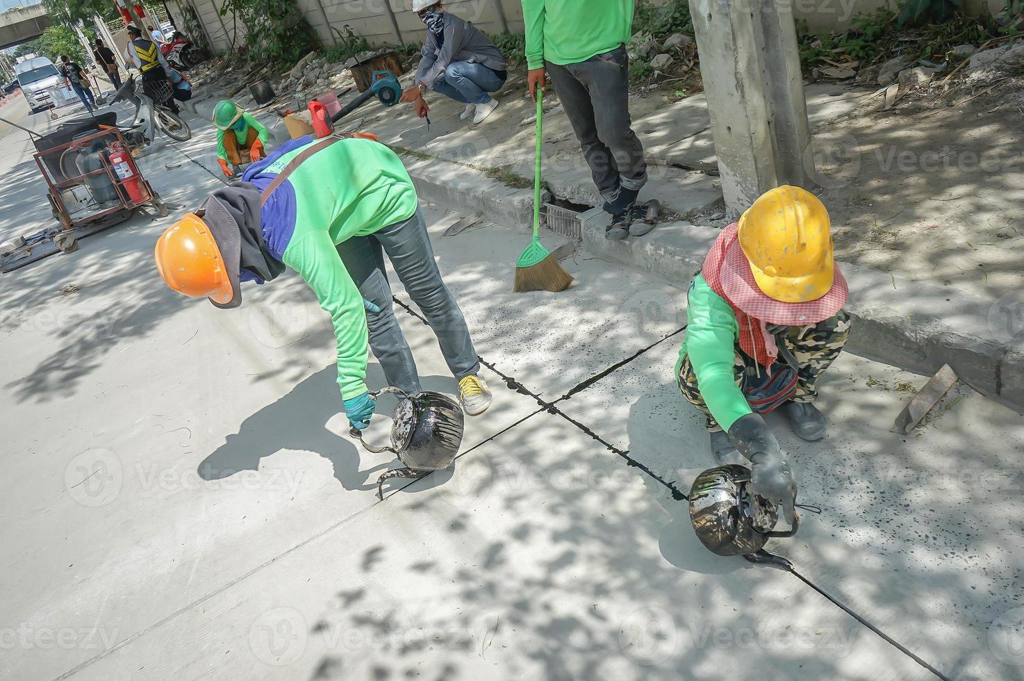 workers drop asphalt liquid into the hole of street. photo