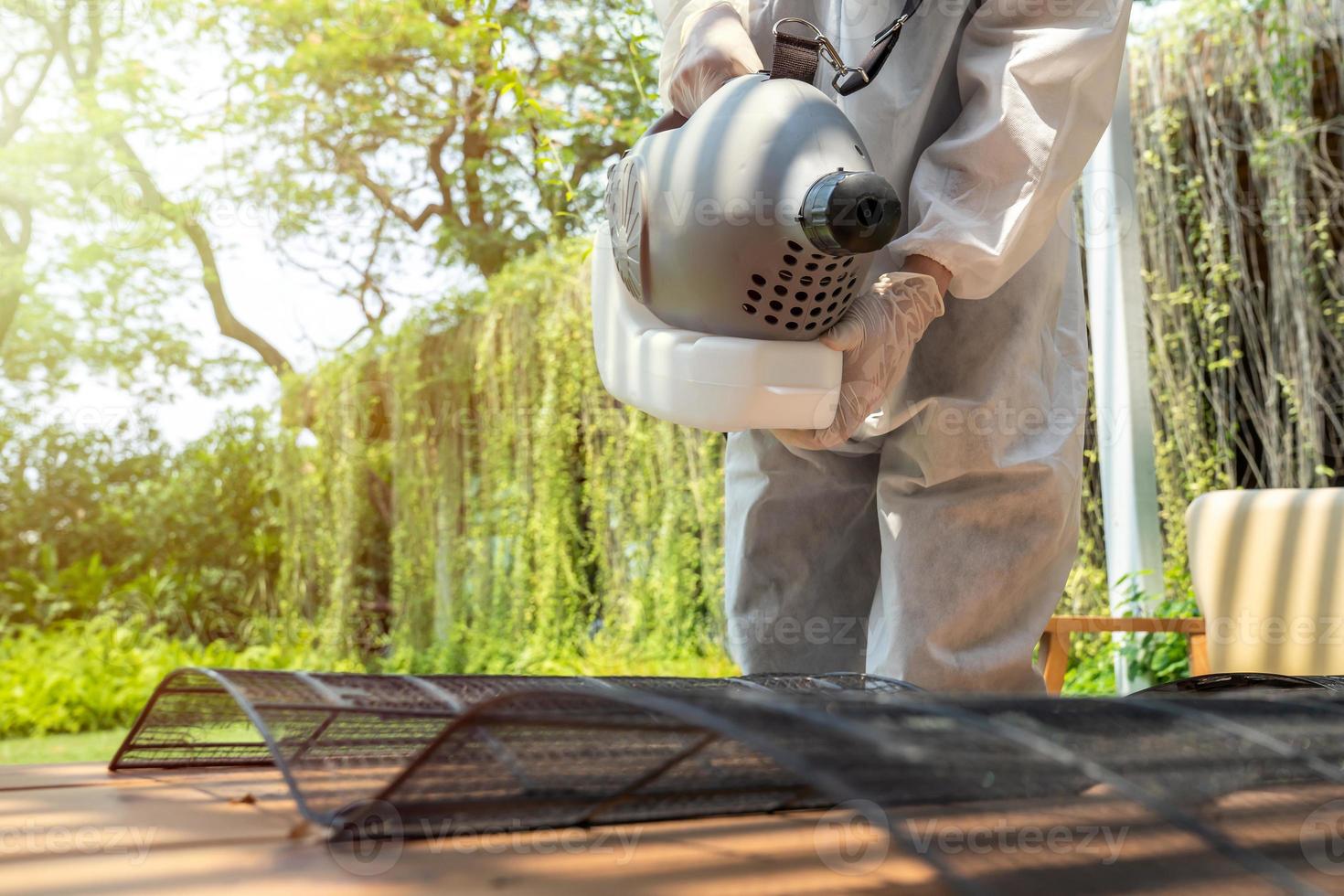 Professional technical man in prevention suit with his sterilizing machine and disinfecting water sprays the air conditioner filter for purifying coronavirus COVID19 photo