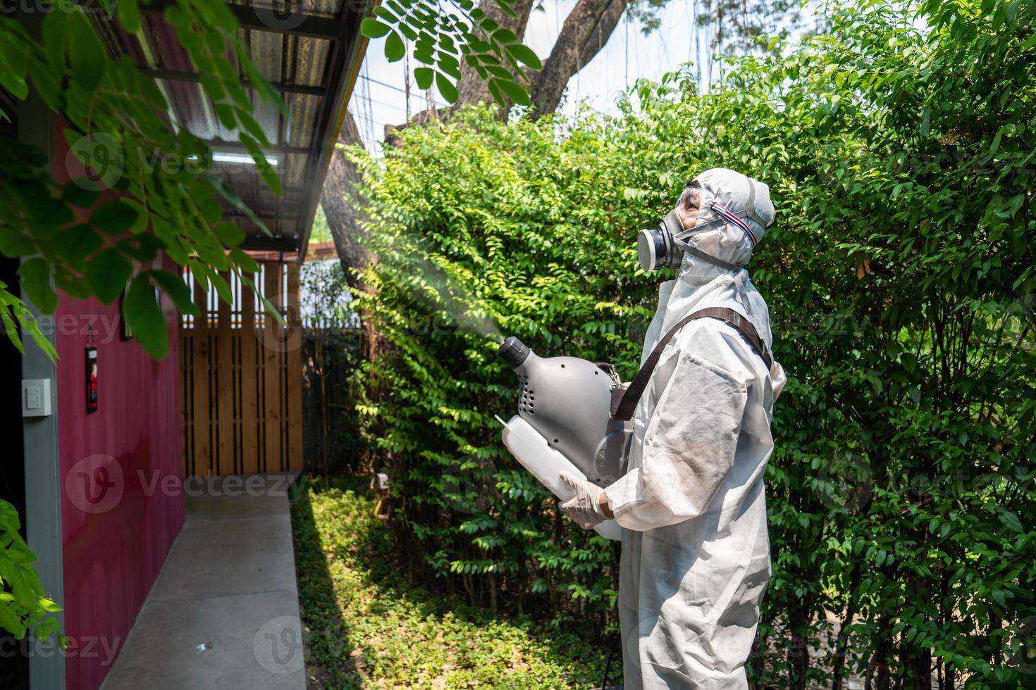 Professional technical man in prevention suit with his sterilizing machine and disinfecting water sprays in the outdoor field for purifying coronavirus COVID19 photo