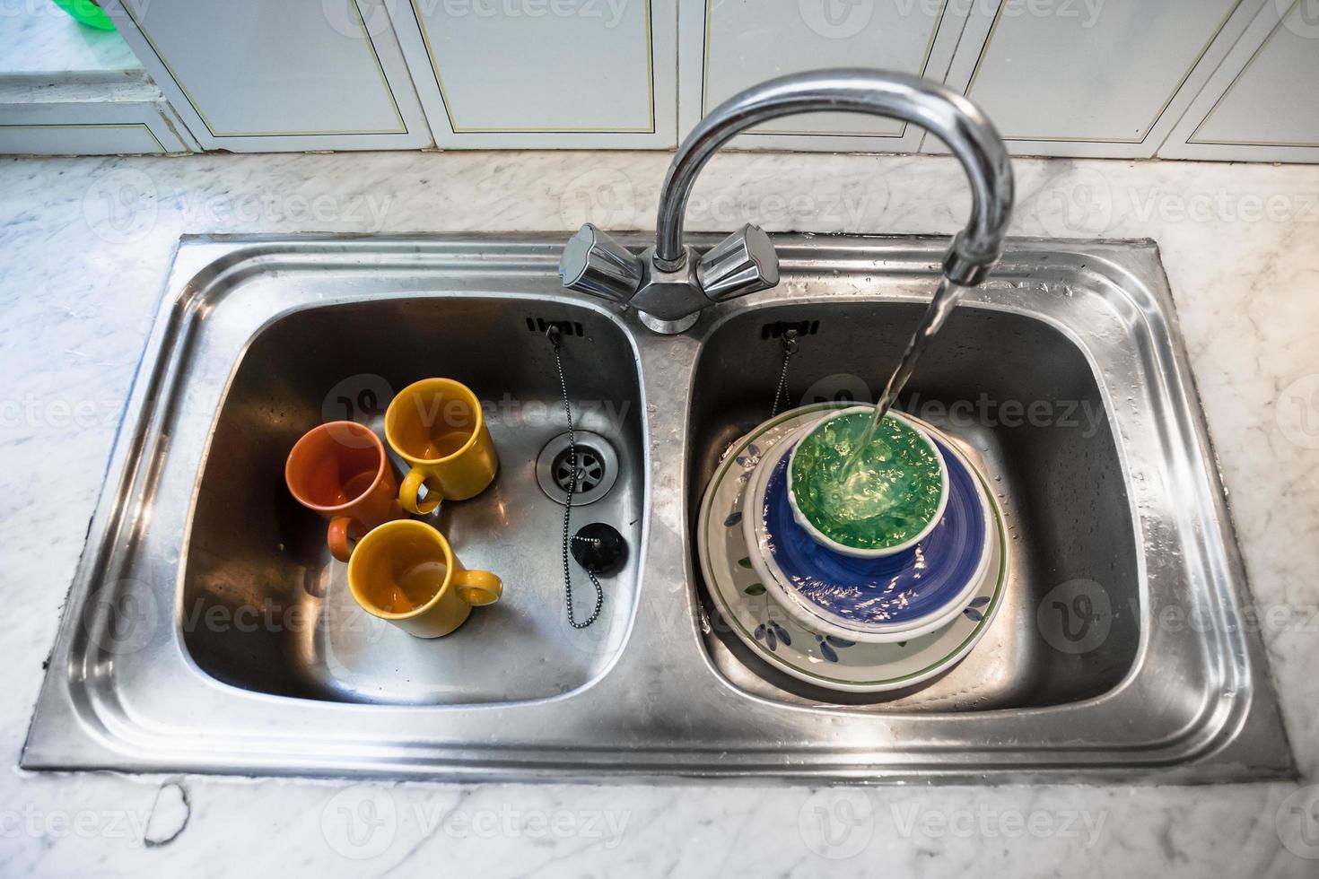 lavado de platos sucios en el fregadero de la cocina foto