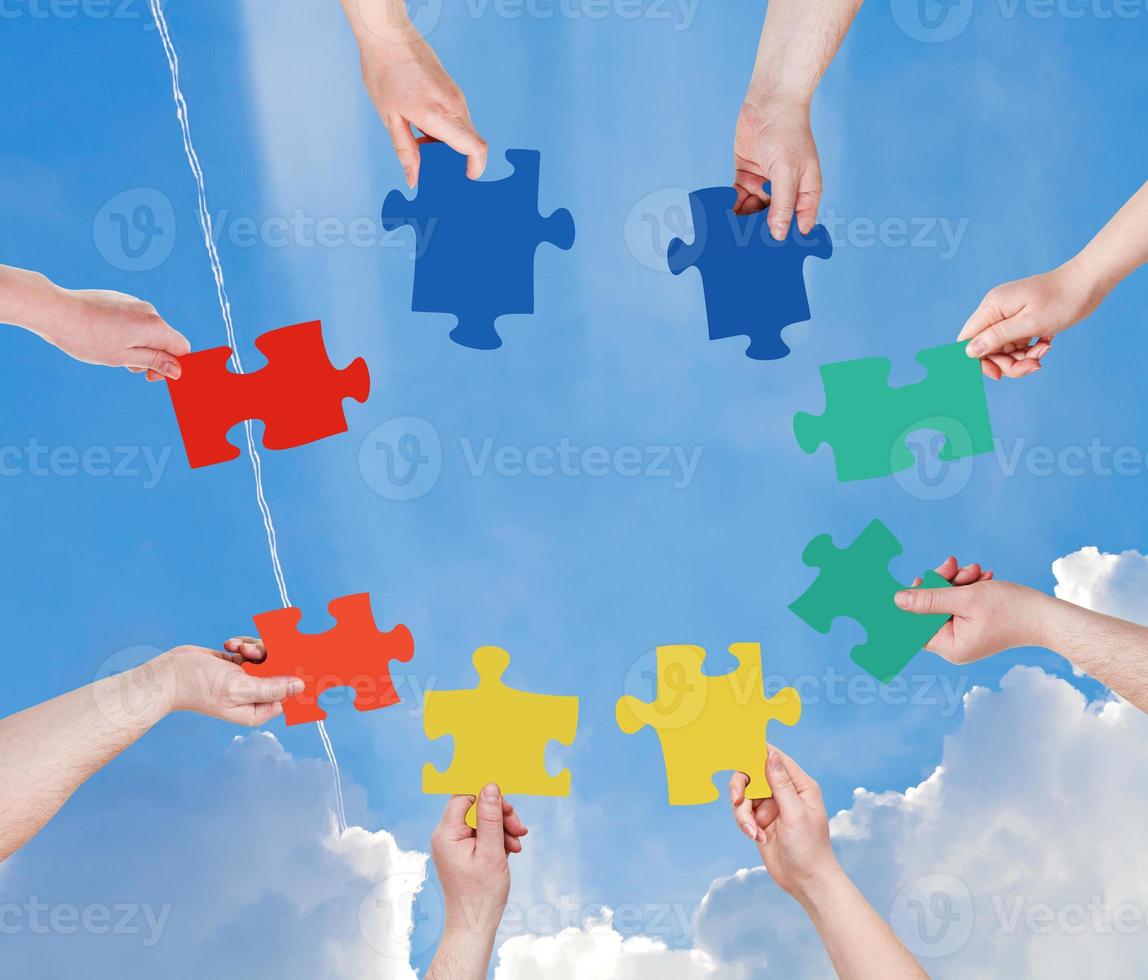 people hands with puzzle pieces with blue sky photo