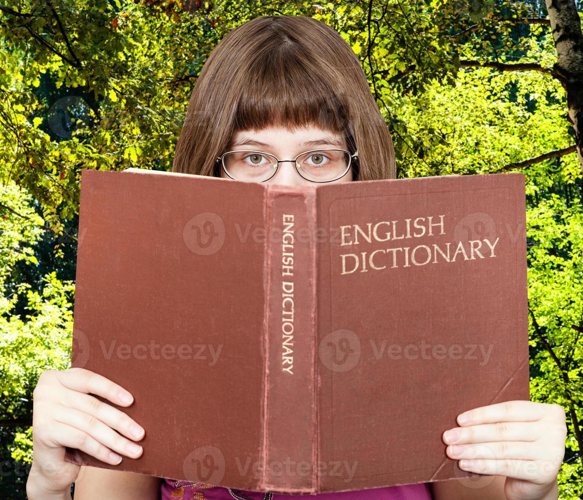 girl looks over English Dictionary and green woods photo