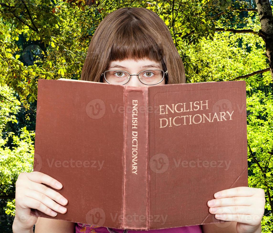 la chica mira el diccionario de inglés y el bosque verde foto