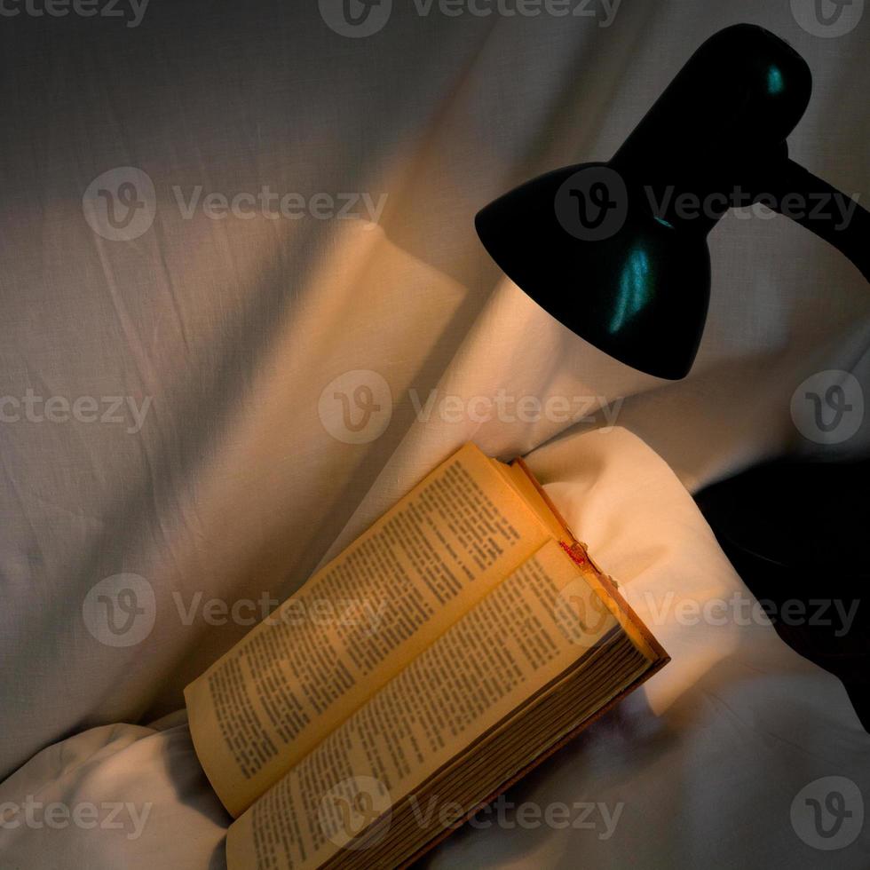 book on pillow lit table lamp photo