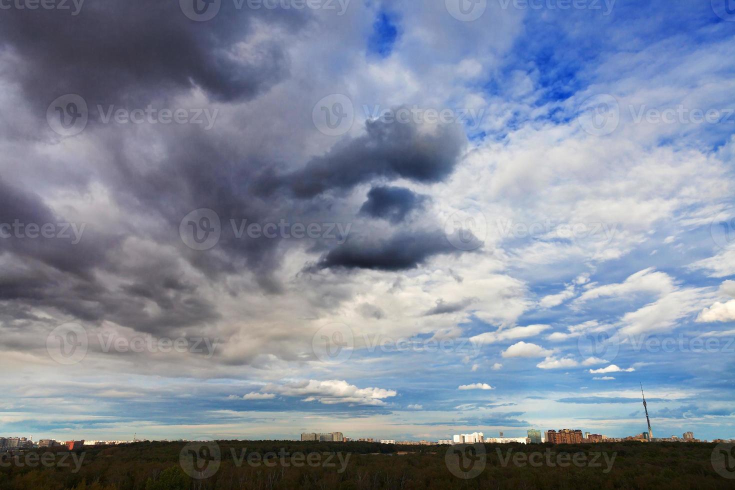 front of grey autumn clouds under city photo