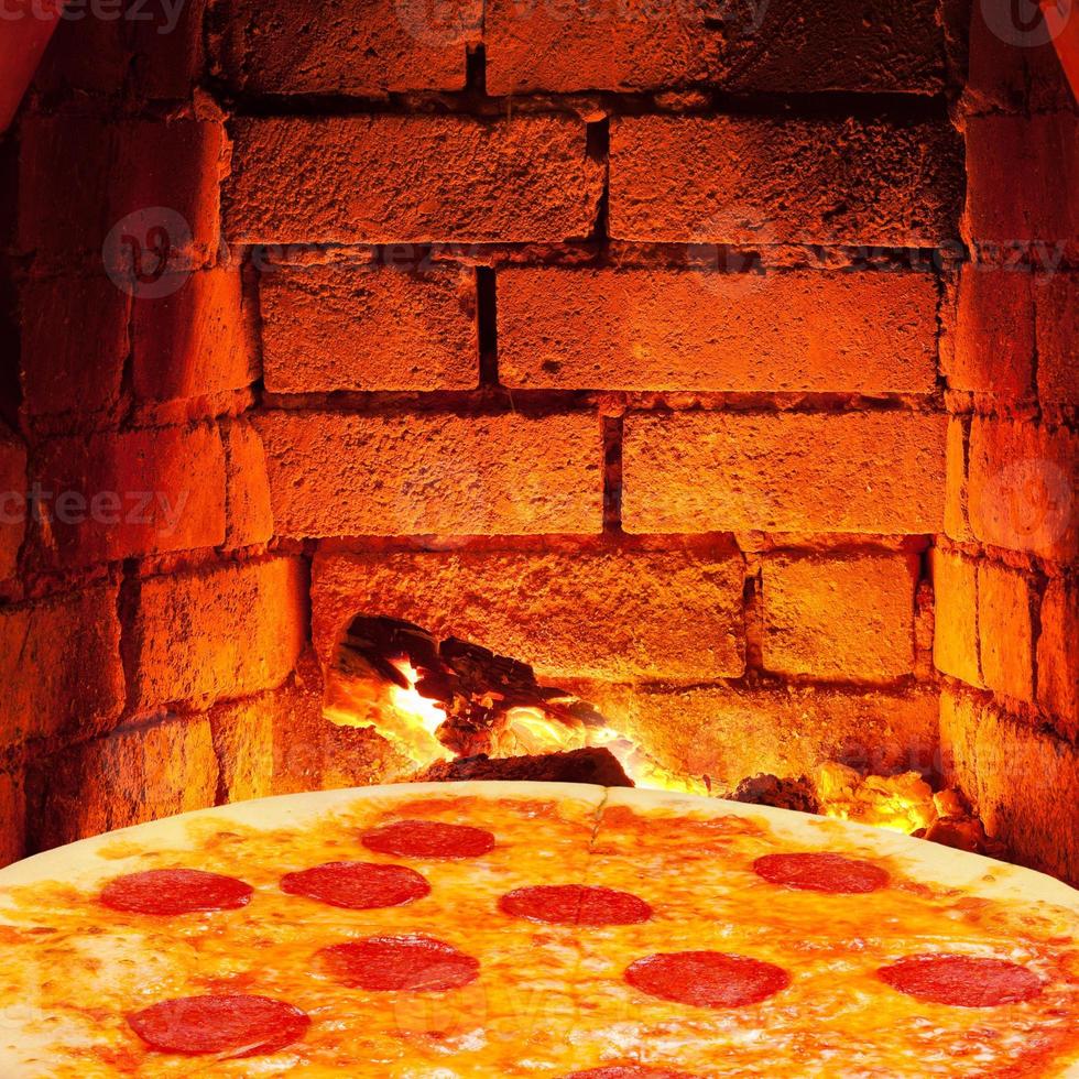 pizza with salami and hot brick wall of oven photo