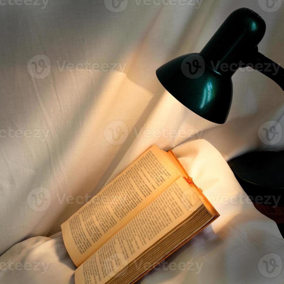 book on pillow lit reading lamp photo