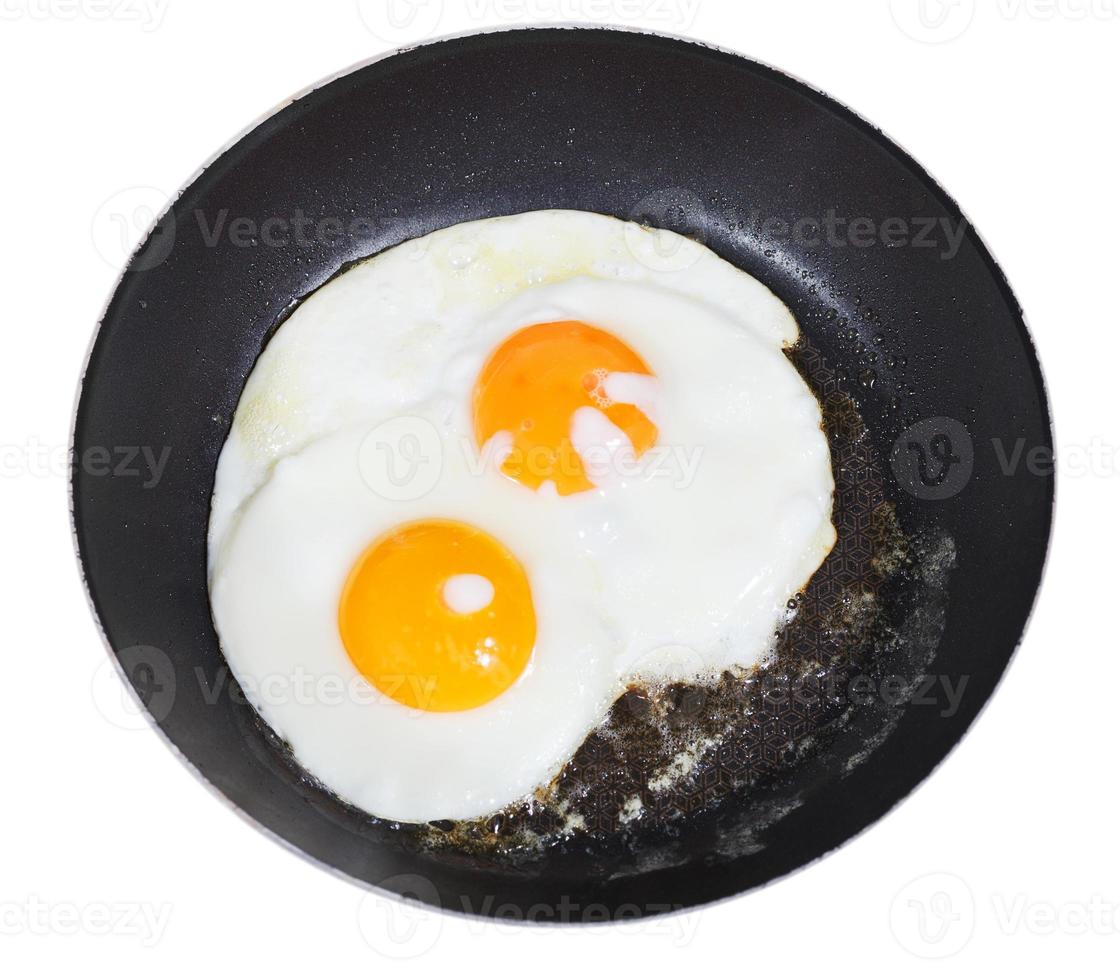 top view of fried eggs in pan isolated on white photo