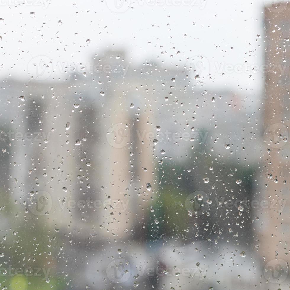 rain drops on window glass and blurred urban house photo