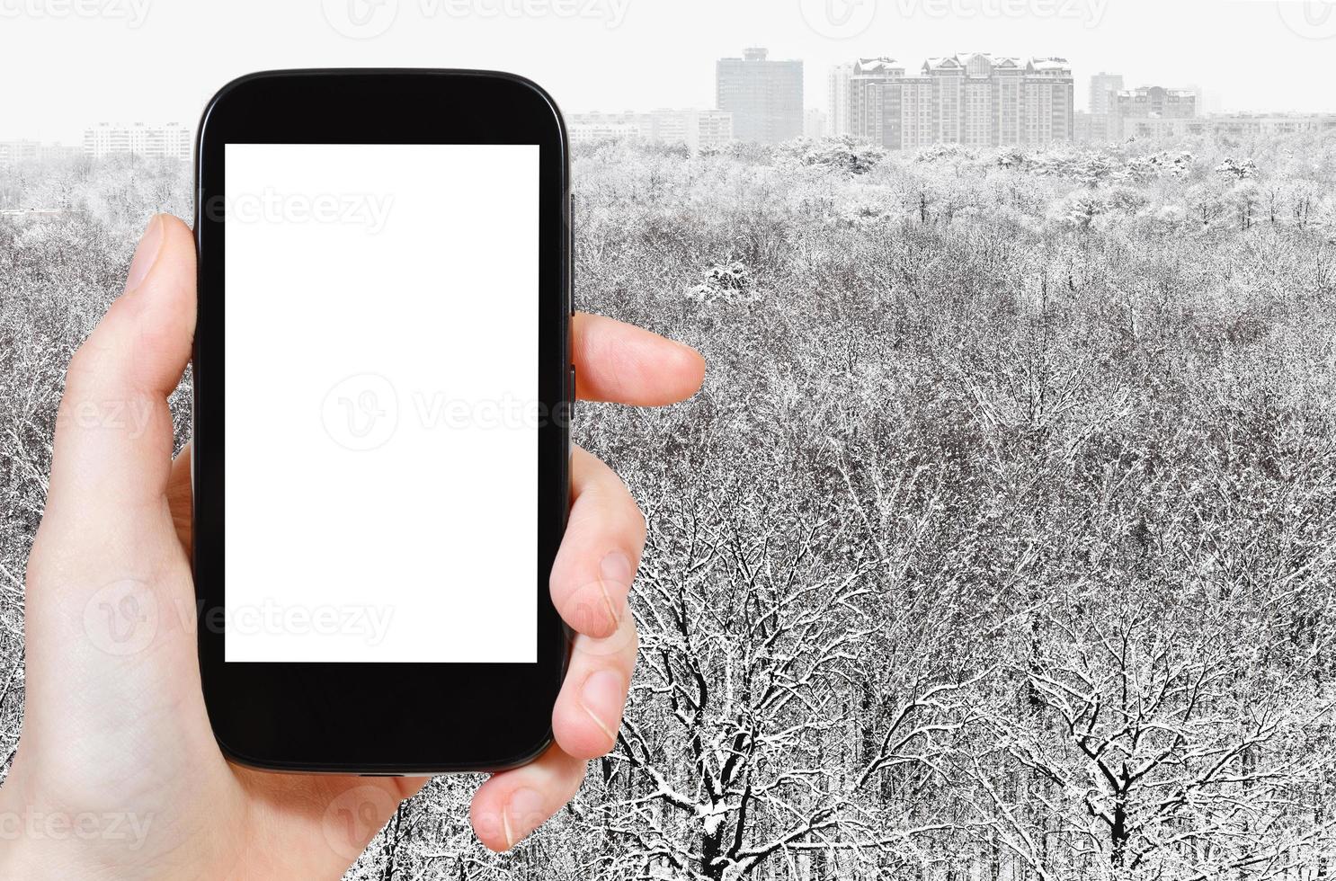 teléfono inteligente y bosque nevado cerca de la ciudad foto