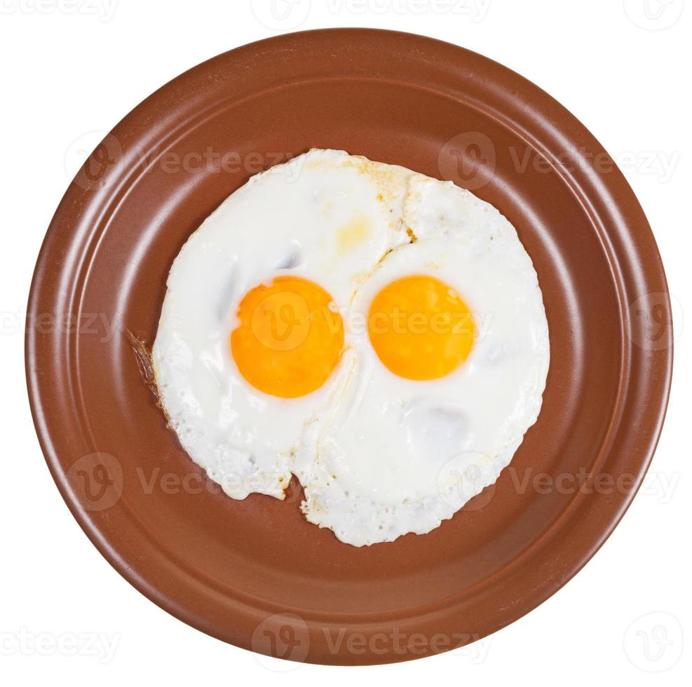 top view of two fried eggs on ceramic brown plate photo