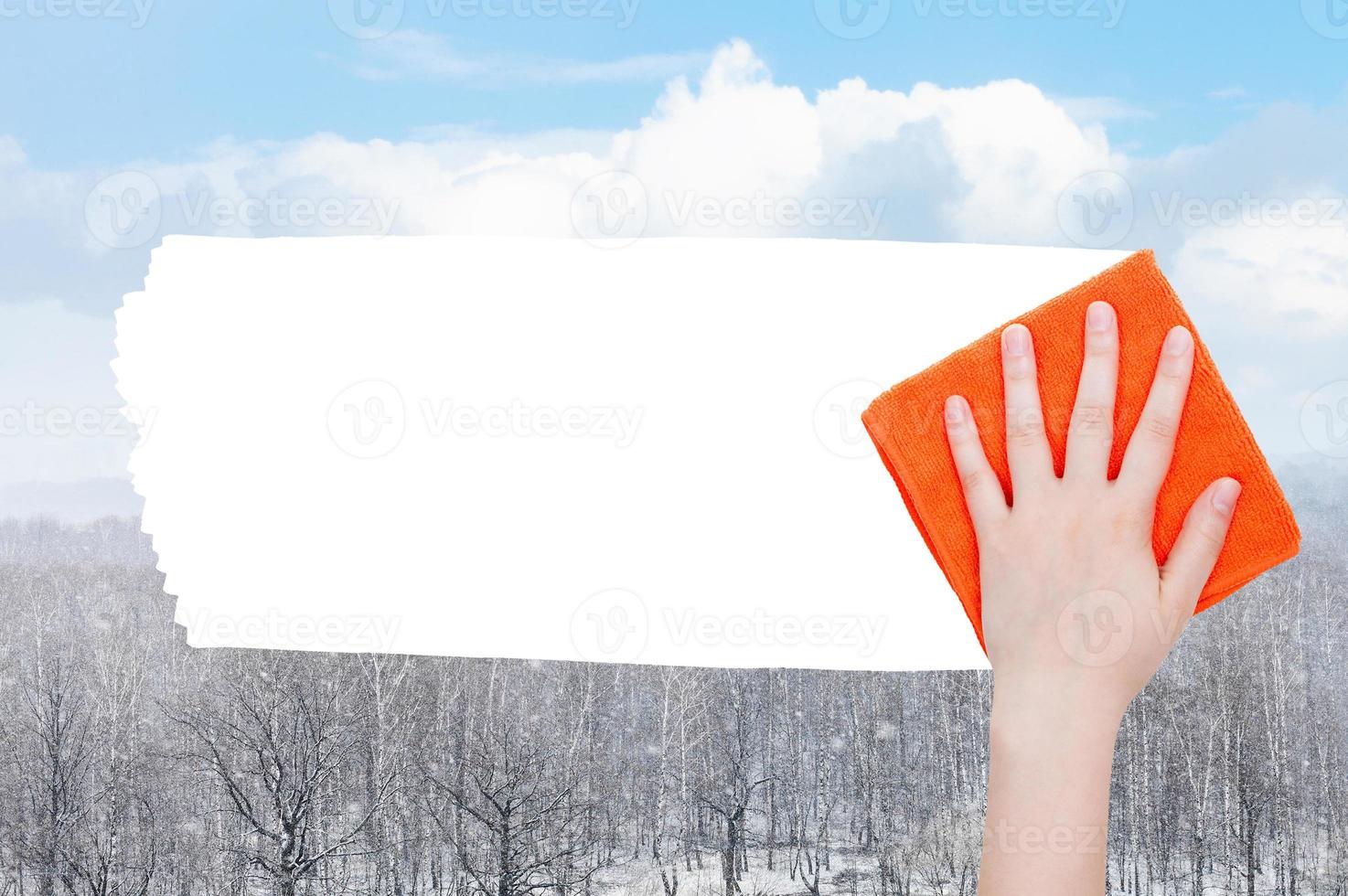 hand deletes snow over forest by orange rag photo