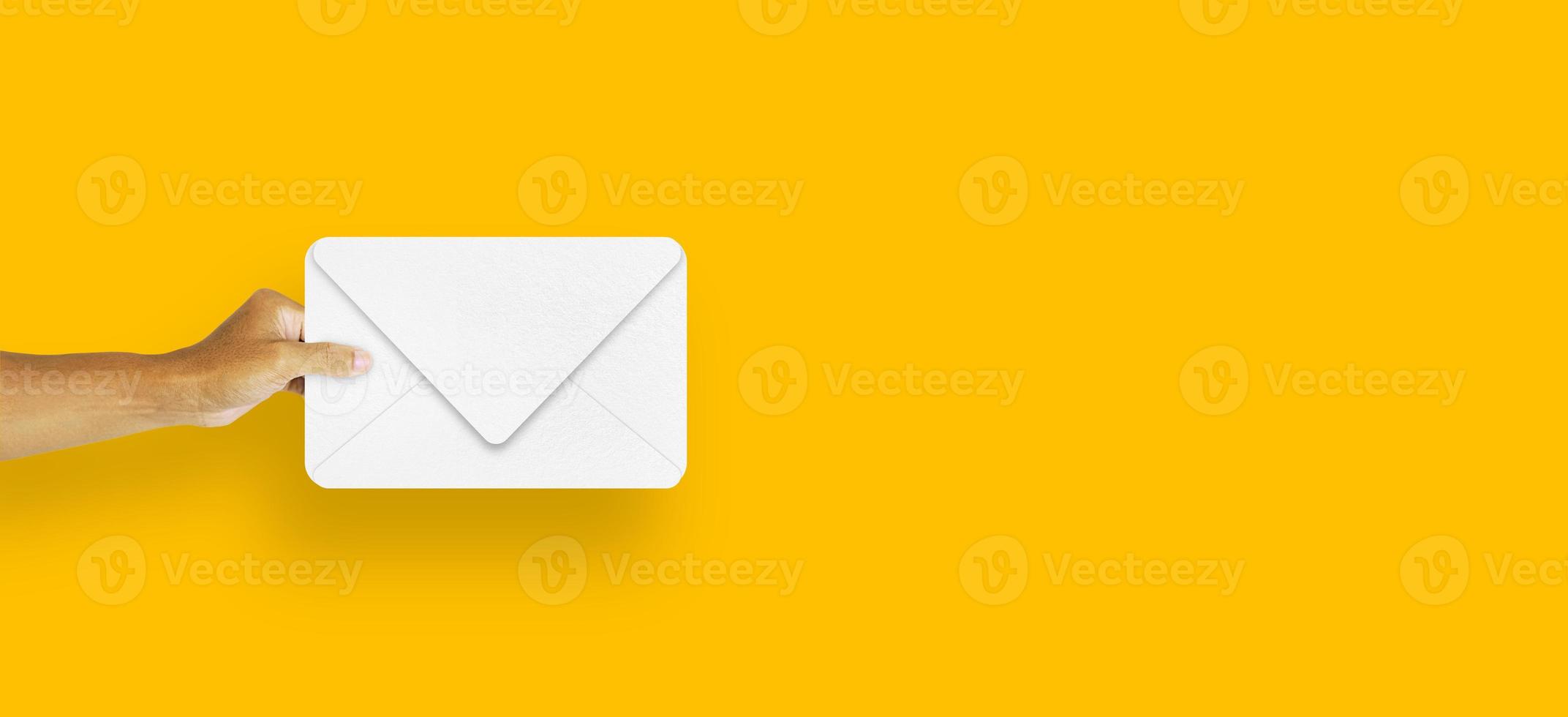 hand holding envelope white paper isolated on yellow background photo