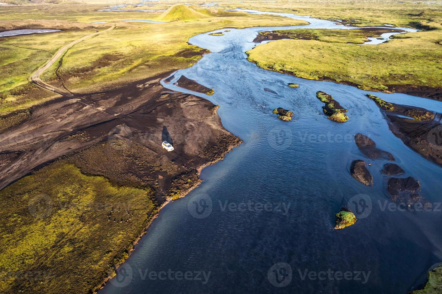 Four wheel drive vehicle parked by the big river crossing in the evening on remote rural at Icelandic Highlands photo