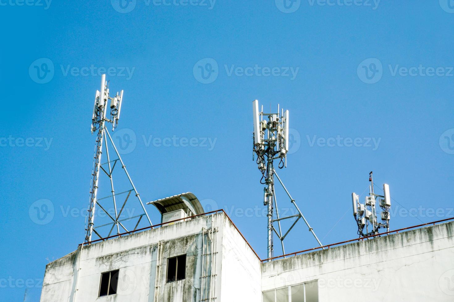 torre de comunicación con antenas en la parte superior del edificio y fondo de cielo azul brillante. foto