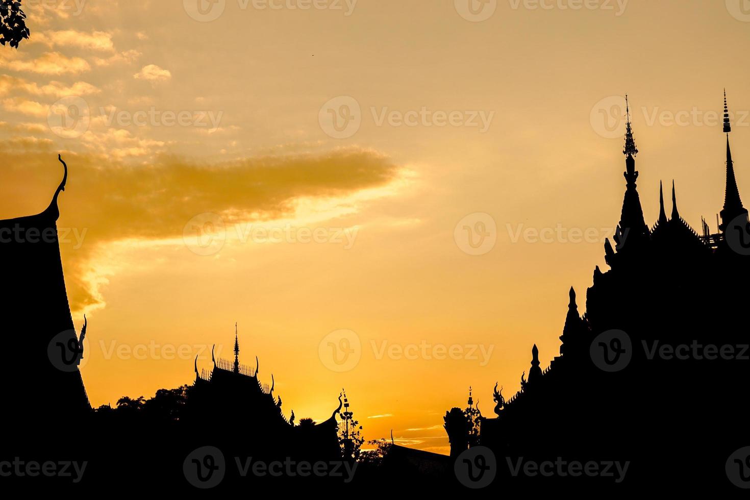 Closeup and crop silhouette of Thai temple on golden sun set sky background. photo