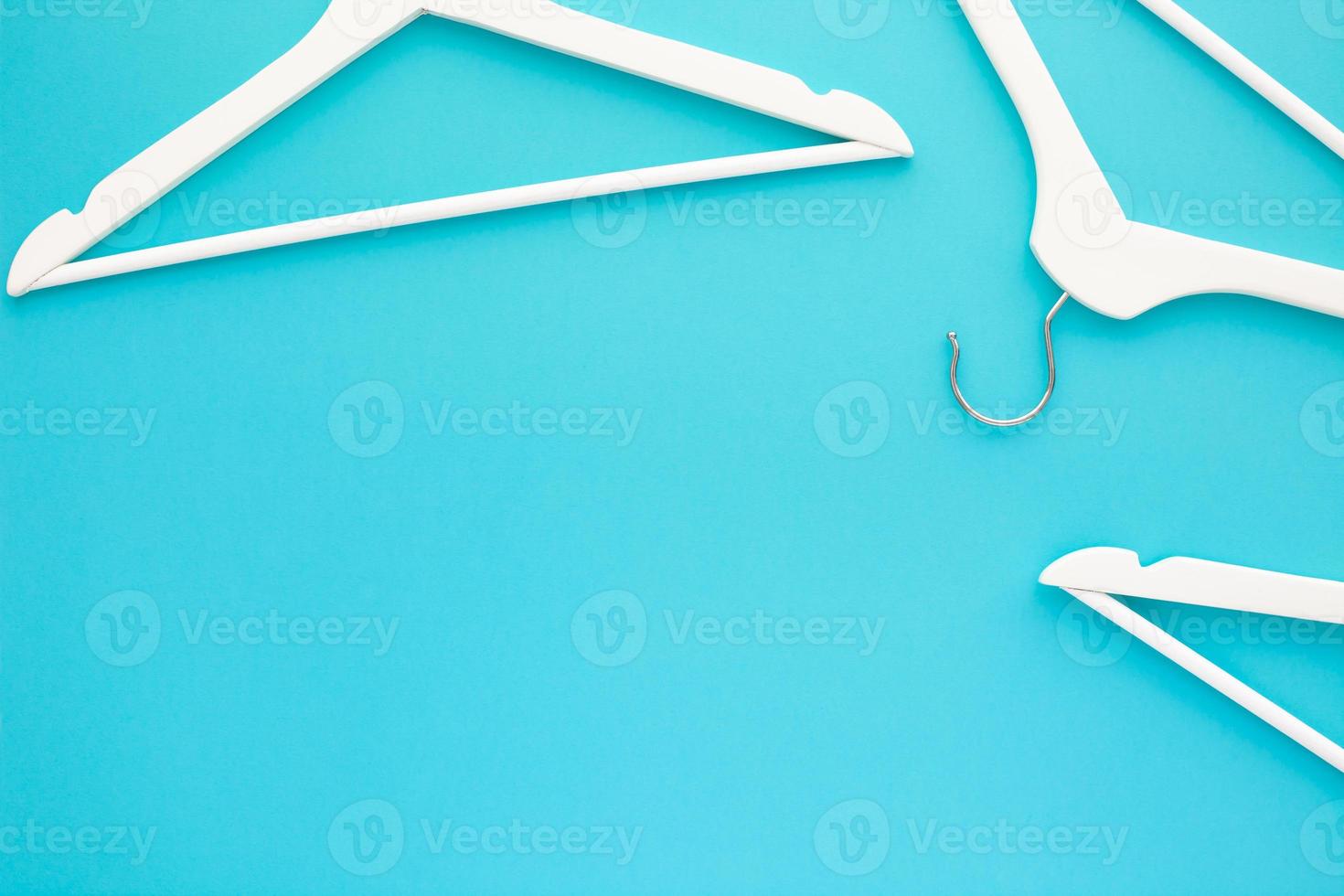 White wooden hangers on blue background photo